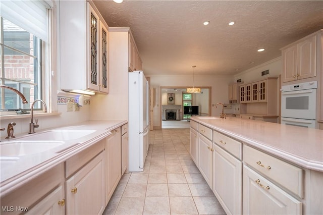 4219 Olde Charted Trl, Poland, OH 44514 - kitchen featuring white appliances, a sink, a textured ceiling, light countertops, and glass insert cabinets