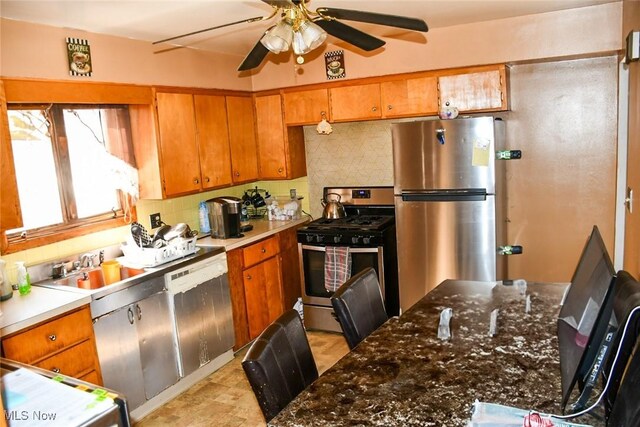 122 21st St NW, Barberton, OH 44203 - kitchen featuring appliances with stainless steel finishes, ceiling fan, decorative backsplash, and brown cabinetry