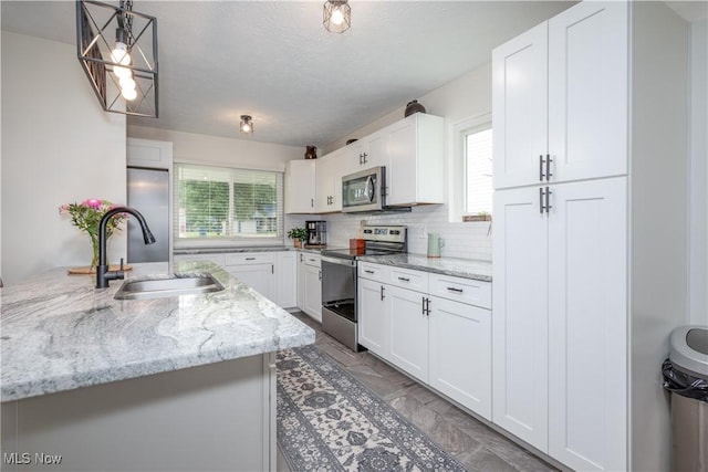 488 Spaulding Dr, Kent, OH 44240 - kitchen featuring appliances with stainless steel finishes, a sink, white cabinets, decorative light fixtures, and backsplash
