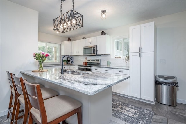 488 Spaulding Dr, Kent, OH 44240 - kitchen with appliances with stainless steel finishes, white cabinets, a sink, a breakfast bar area, and light stone countertops