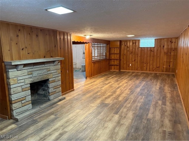 22561 Chardon Rd, Euclid, OH 44117 - unfurnished living room featuring a textured ceiling, wood finished floors, wooden walls, and a fireplace