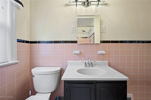 14300 Bidwell Ave, Cleveland, OH 44111 - bathroom with tile walls, toilet, vanity, and a wainscoted wall