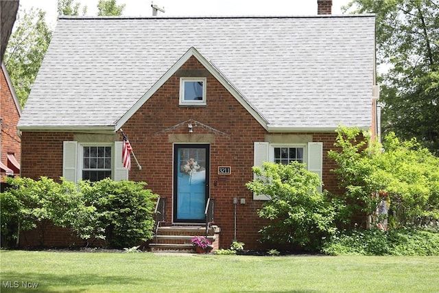 3211 W 140th St, Cleveland, OH 44111 - tudor house with brick siding, entry steps, a front yard, a chimney, and a shingled roof