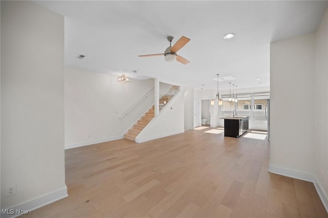 1257 W 75th St Unit D1257, Cleveland, OH 44102 - unfurnished living room featuring a sink, baseboards, recessed lighting, stairs, and light wood-type flooring