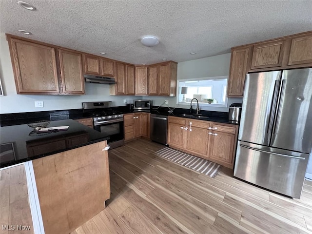 2187 State Route 550, Cutler, OH 45724 - kitchen with stainless steel appliances, under cabinet range hood, light wood-style flooring, dark countertops, and a textured ceiling