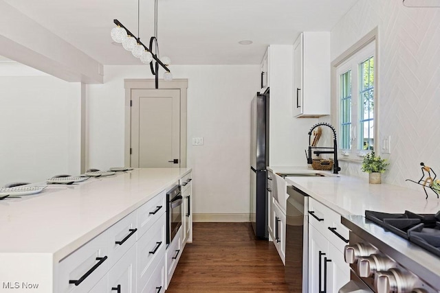 21262 S Woodland Rd, Shaker Heights, OH 44122 - kitchen featuring appliances with stainless steel finishes, light countertops, a sink, white cabinets, and dark wood-style flooring