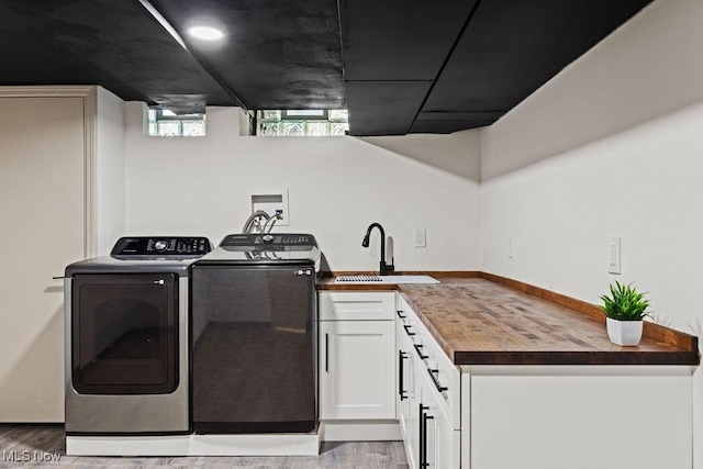 21262 S Woodland Rd, Shaker Heights, OH 44122 - laundry room featuring washer and clothes dryer, light wood-style floors, and cabinet space