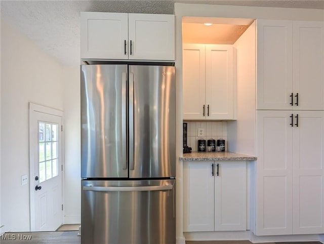 3509 Jerrold Blvd, Brunswick, OH 44212 - kitchen with freestanding refrigerator, backsplash, white cabinetry, light stone counters, and a textured ceiling