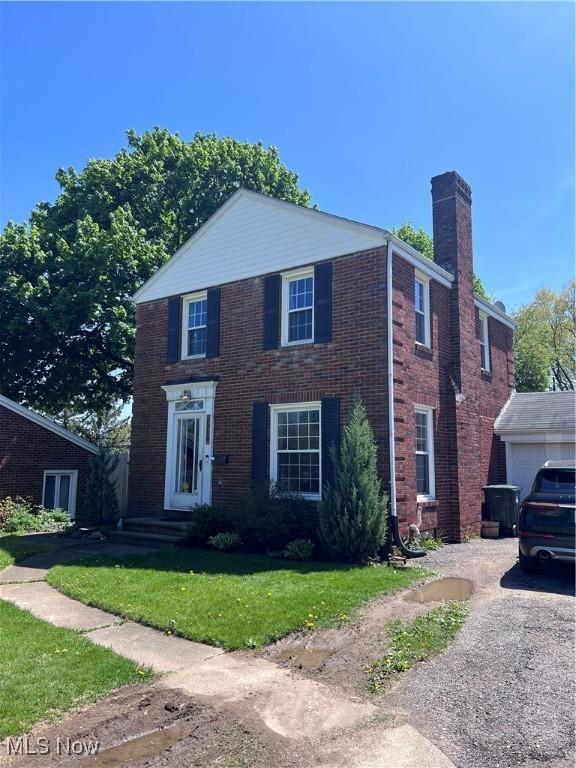 1218 24th St NE, Canton, OH 44714 - view of front of home featuring a chimney, a front yard, brick siding, driveway, and a garage