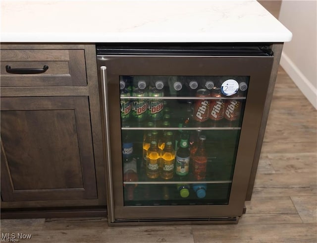 646 Ridgewood Dr, Coshocton, OH 43812 - kitchen view of beverage cooler, dark brown cabinetry, and wood finished floors