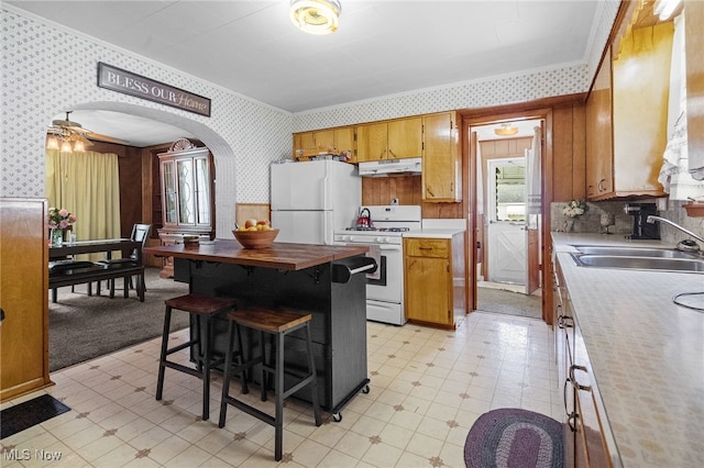917 Park Ave SW, Canton, OH 44706 - kitchen with white appliances, wallpapered walls, a sink, under cabinet range hood, and brown cabinets