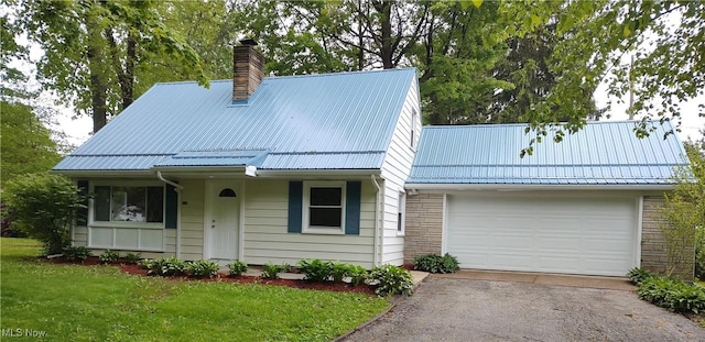 1750 Trinity Rd, Madison, OH 44057 - view of front of house with a chimney, asphalt driveway, metal roof, and a garage