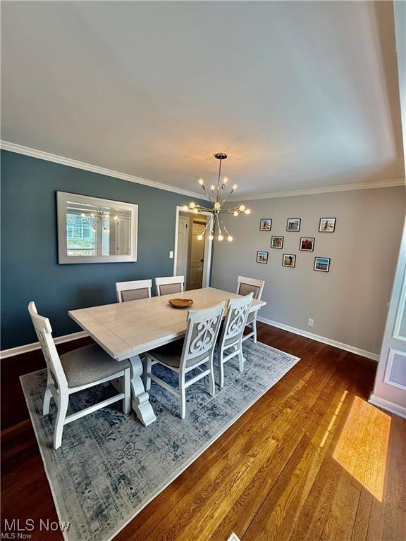 6911 Post Ln, Hudson, OH 44236 - dining space featuring a chandelier, baseboards, dark wood-type flooring, and ornamental molding