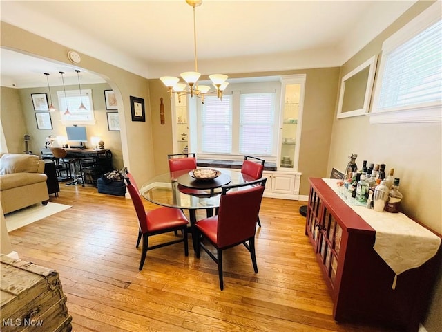 1630 Olivewood Ave, Lakewood, OH 44107 - dining room with a chandelier, light wood-style floors, arched walkways, and plenty of natural light