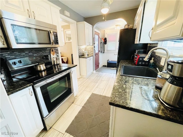 1630 Olivewood Ave, Lakewood, OH 44107 - kitchen featuring stainless steel appliances, tasteful backsplash, white cabinets, a sink, and arched walkways