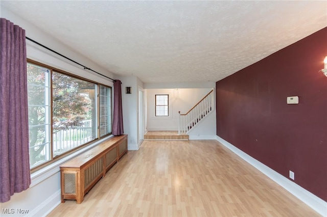 2224 Emily Ave, Lakewood, OH 44107 - unfurnished living room with light wood-style floors, baseboards, stairway, and a textured ceiling