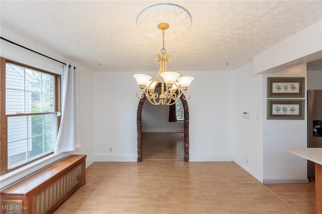 2224 Emily Ave, Lakewood, OH 44107 - unfurnished dining area featuring radiator heating unit, light wood-style floors, a chandelier, baseboards, and a textured ceiling