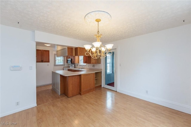 2224 Emily Ave, Lakewood, OH 44107 - kitchen with brown cabinets, a chandelier, electric range, stainless steel microwave, and a peninsula