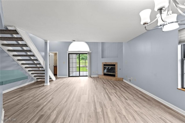 6465 Saint Andrews Dr Unit 6, Canfield, OH 44406 - unfurnished living room featuring stairs, wood finished floors, a chandelier, baseboards, and a glass covered fireplace