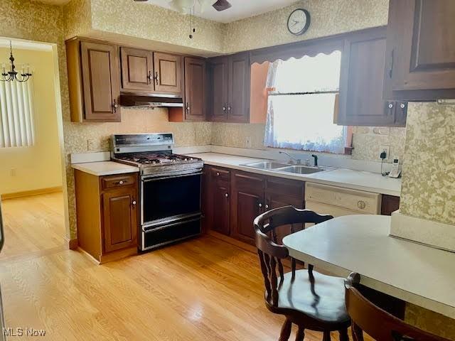 1148 Miami Ave, Youngstown, OH 44505 - kitchen featuring range with gas cooktop, under cabinet range hood, light wood-style flooring, light countertops, and backsplash