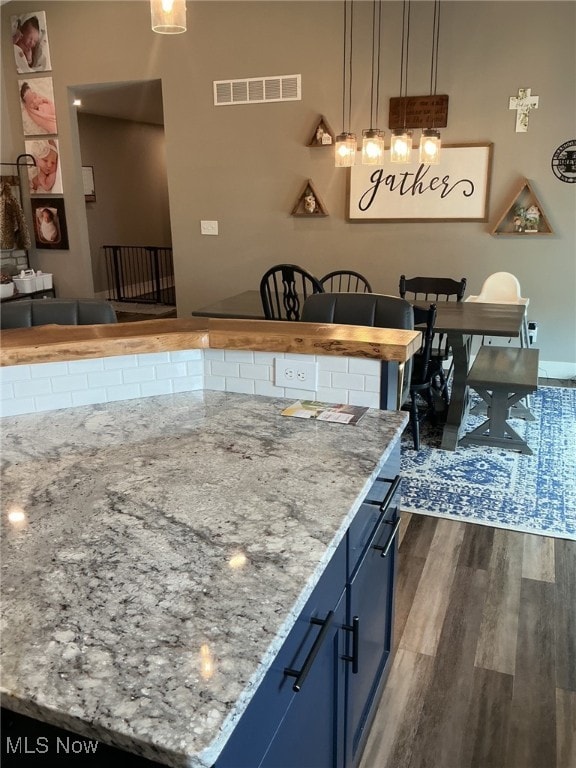 7030 Jones Rd, Nashport, OH 43830 - kitchen with blue cabinets, dark wood-style flooring, light stone counters, and decorative light fixtures