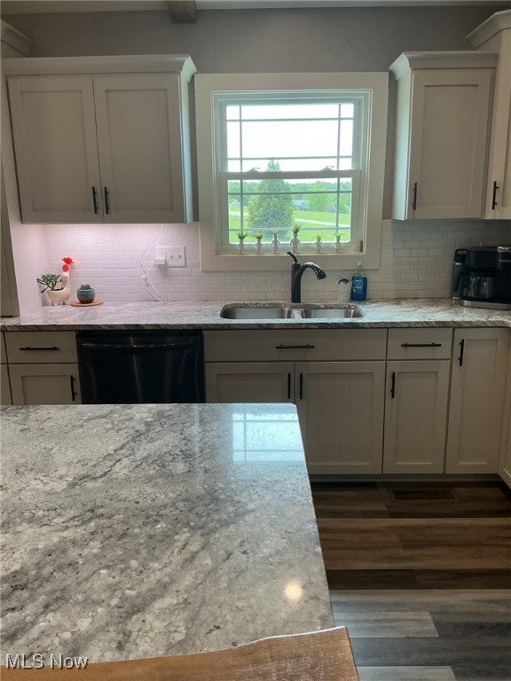 7030 Jones Rd, Nashport, OH 43830 - kitchen featuring black dishwasher, a sink, dark wood-style flooring, tasteful backsplash, and light stone countertops