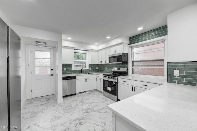 2330 Traymore Rd, University Heights, OH 44118 - kitchen featuring stainless steel appliances, light marble finish floors, white cabinets, decorative backsplash, and a sink
