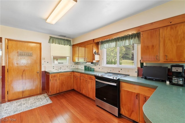 4937 Stevens Rd, Akron, OH 44319 - kitchen with stainless steel range oven, light wood-type flooring, backsplash, a sink, and brown cabinets