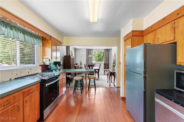 4937 Stevens Rd, Akron, OH 44319 - kitchen featuring stainless steel appliances, light wood-style floors, brown cabinets, and decorative backsplash
