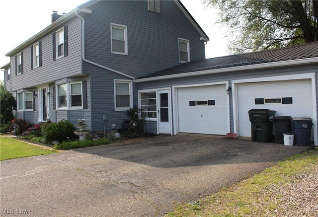230 Rivercrest Dr, Coshocton, OH 43812 - view of front of home featuring asphalt driveway, a chimney, an attached garage, and metal roof