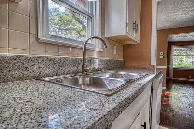8208 Vista Ave, Garfield Heights, OH 44125 - kitchen featuring a sink, stainless steel dishwasher, white cabinets, backsplash, and a textured ceiling