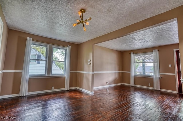 8208 Vista Ave, Garfield Heights, OH 44125 - empty room featuring healthy amount of natural light, a textured ceiling, hardwood / wood-style floors, and baseboards