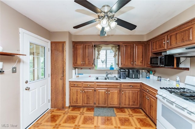 29431 Fairway Blvd, Willowick, OH 44095 - kitchen featuring white gas range oven, stainless steel microwave, under cabinet range hood, light countertops, and brown cabinetry