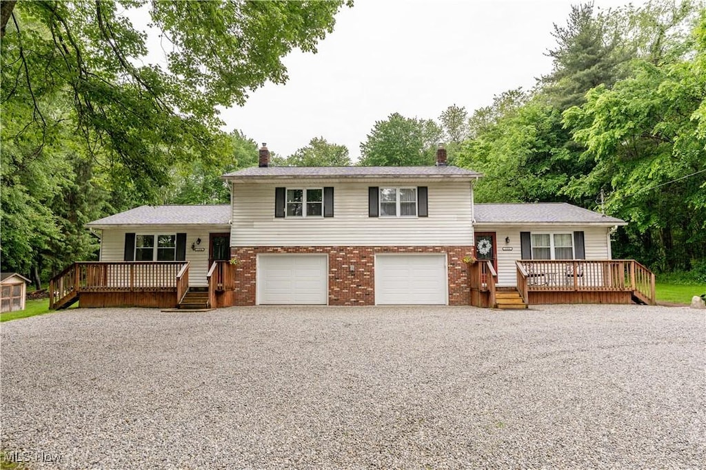 1354-1358 Vanderhoof Rd, Barberton, OH 44203 - tri-level home with a chimney, gravel driveway, a wooden deck, brick siding, and view of scattered trees