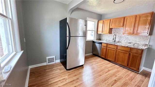 711 E 212th St, Euclid, OH 44119 - kitchen with appliances with stainless steel finishes, a sink, backsplash, light wood-type flooring, and baseboards