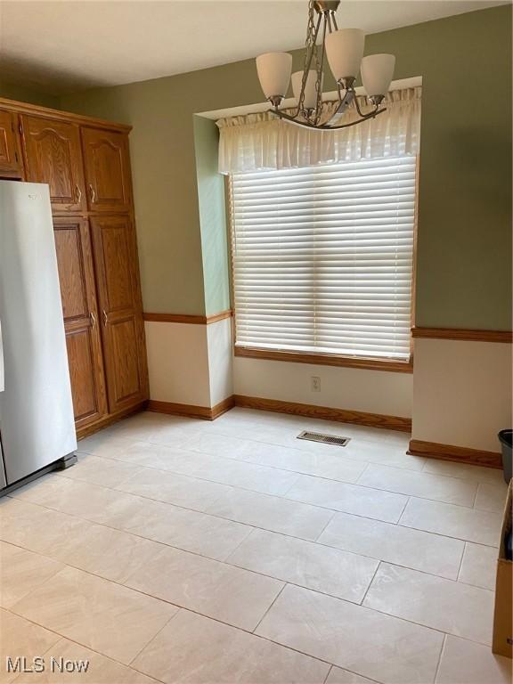 579 Glenmere Pl, Barberton, OH 44203 - unfurnished dining area featuring healthy amount of natural light, a chandelier, and baseboards