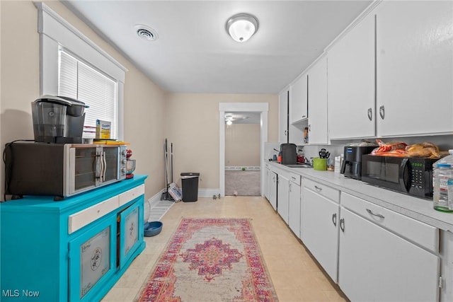 832 Wellman Ave SE, Massillon, OH 44646 - kitchen with white cabinets, black microwave, light countertops, and baseboards
