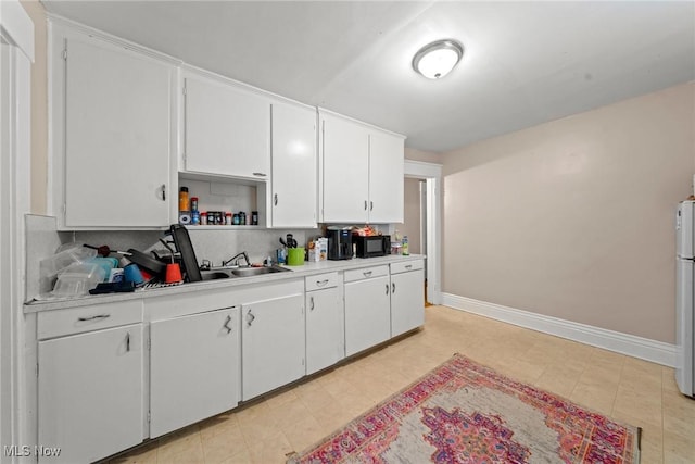 832 Wellman Ave SE, Massillon, OH 44646 - kitchen with black microwave, light countertops, backsplash, and white cabinets