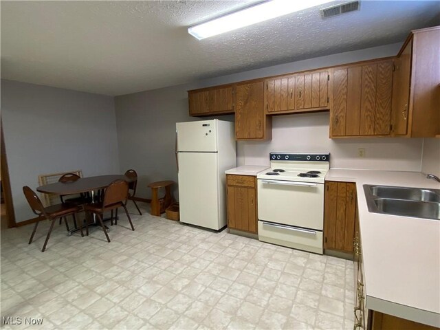 14035 Dover Rd, Apple Creek, OH 44606 - kitchen with white appliances, a sink, brown cabinetry, light countertops, and light flooring