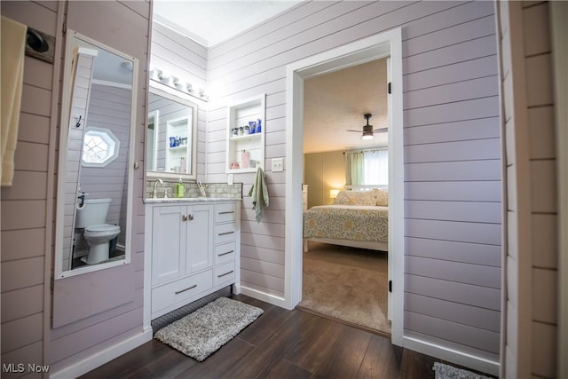5725 Joleda Dr SW, Canton, OH 44706 - ensuite bathroom featuring wood walls, toilet, vanity, wood finished floors, and a ceiling fan