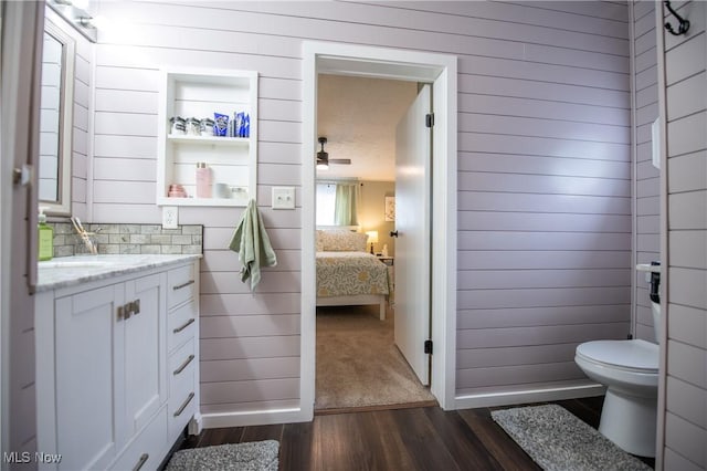 5725 Joleda Dr SW, Canton, OH 44706 - ensuite bathroom with toilet, wood finished floors, vanity, wooden walls, and ceiling fan