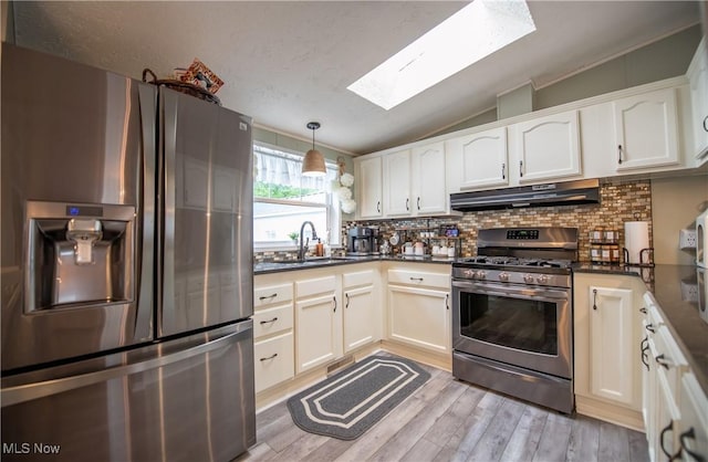 5725 Joleda Dr SW, Canton, OH 44706 - kitchen featuring appliances with stainless steel finishes, a skylight, under cabinet range hood, dark countertops, and lofted ceiling