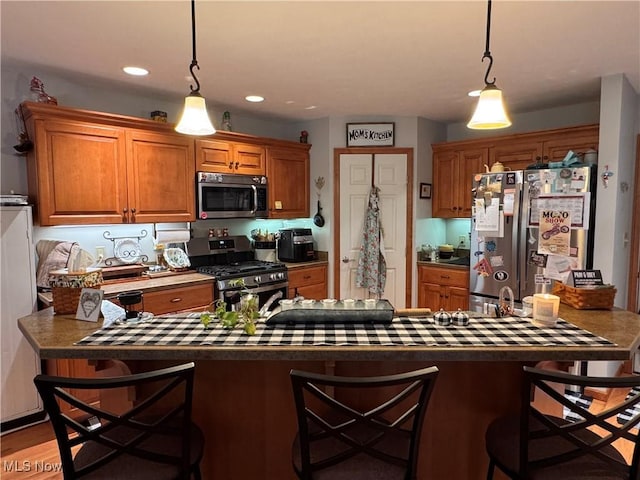 617 Wedgewood Way Unit 617, Millersburg, OH 44654 - kitchen with appliances with stainless steel finishes, brown cabinetry, a kitchen breakfast bar, dark countertops, and recessed lighting