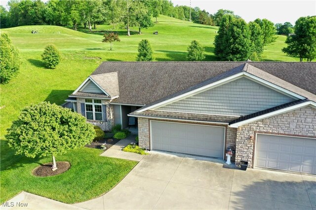 617 Wedgewood Way Unit 617, Millersburg, OH 44654 - view of front facade featuring driveway, an attached garage, stone siding, a front yard, and a shingled roof