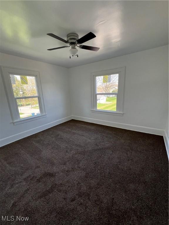 764 Jones St, Hubbard, OH 44425 - empty room featuring healthy amount of natural light, baseboards, a ceiling fan, and dark colored carpet