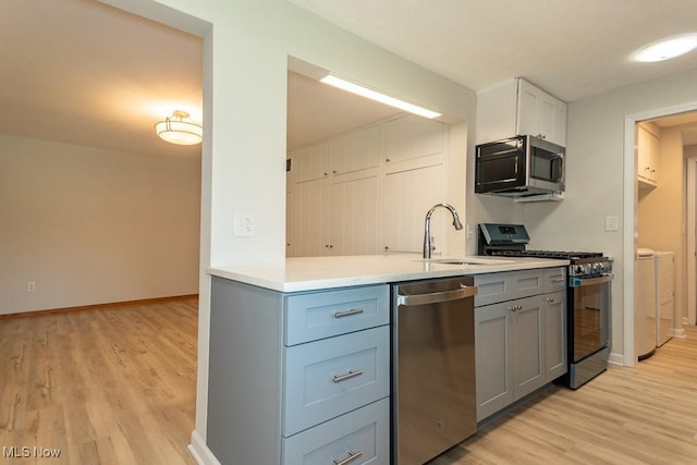 26 Middleton Dr, Painesville Township, OH 44077 - kitchen featuring appliances with stainless steel finishes, a sink, gray cabinetry, light wood-type flooring, and light countertops