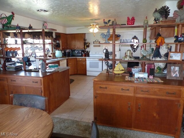 988 E Turkeyfoot Lake Rd, Green, OH 44312 - kitchen featuring white appliances, a textured ceiling, ceiling fan, light tile patterned floors, and brown cabinets