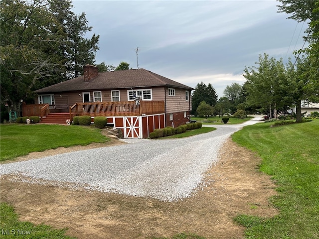 988 E Turkeyfoot Lake Rd, Green, OH 44312 - view of front of property with a chimney, gravel driveway, a front lawn, a deck, and an outbuilding