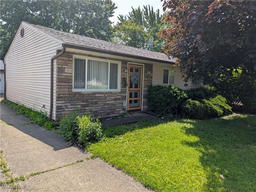 1009 E 347th St, Eastlake, OH 44095 - view of front of house with stone siding, a front lawn, and a shingled roof