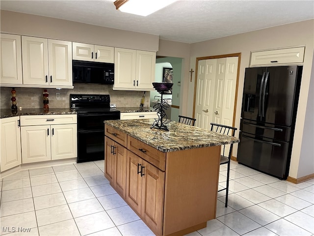 12701 Gordon St, North Royalton, OH 44133 - kitchen with black appliances, a breakfast bar, dark stone countertops, light tile patterned floors, and tasteful backsplash